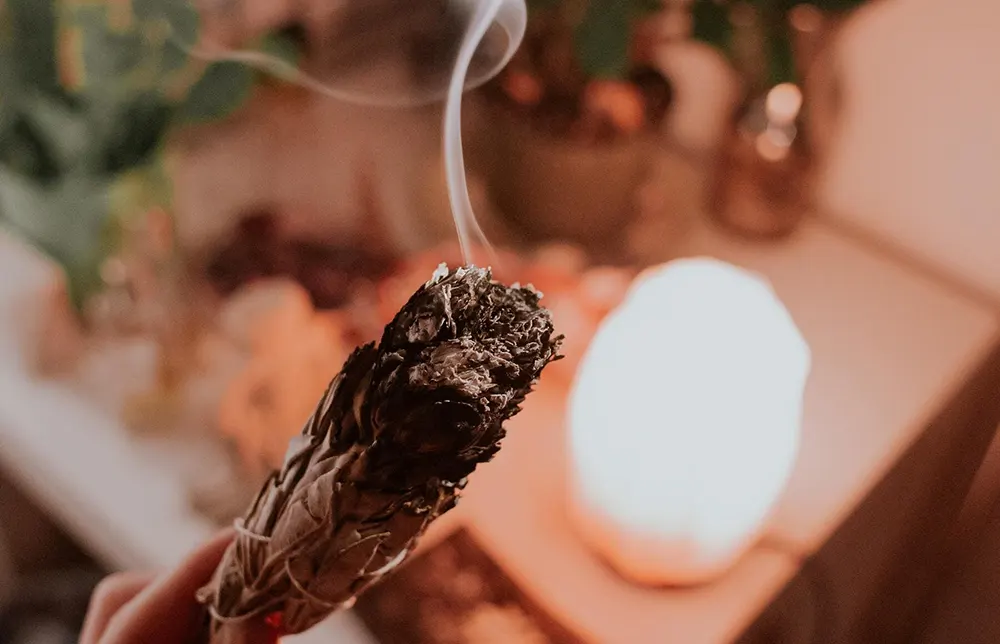 How to cleanse tarot deck with sage smoke over spread-out cards on wooden altar